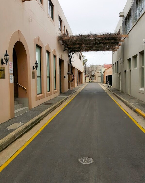 A street with buildings on either side, featuring arched doorways and windows.