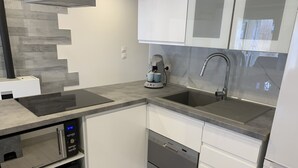 Een moderne keuken met een inbouwoven, magnetron en vaatwasser, een koffiezetapparaat en een roestvrijstalen spoelbak.