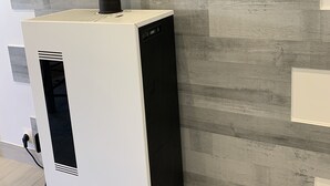 Een moderne, witte en zwarte verwarming tegen een grijze houten wand.