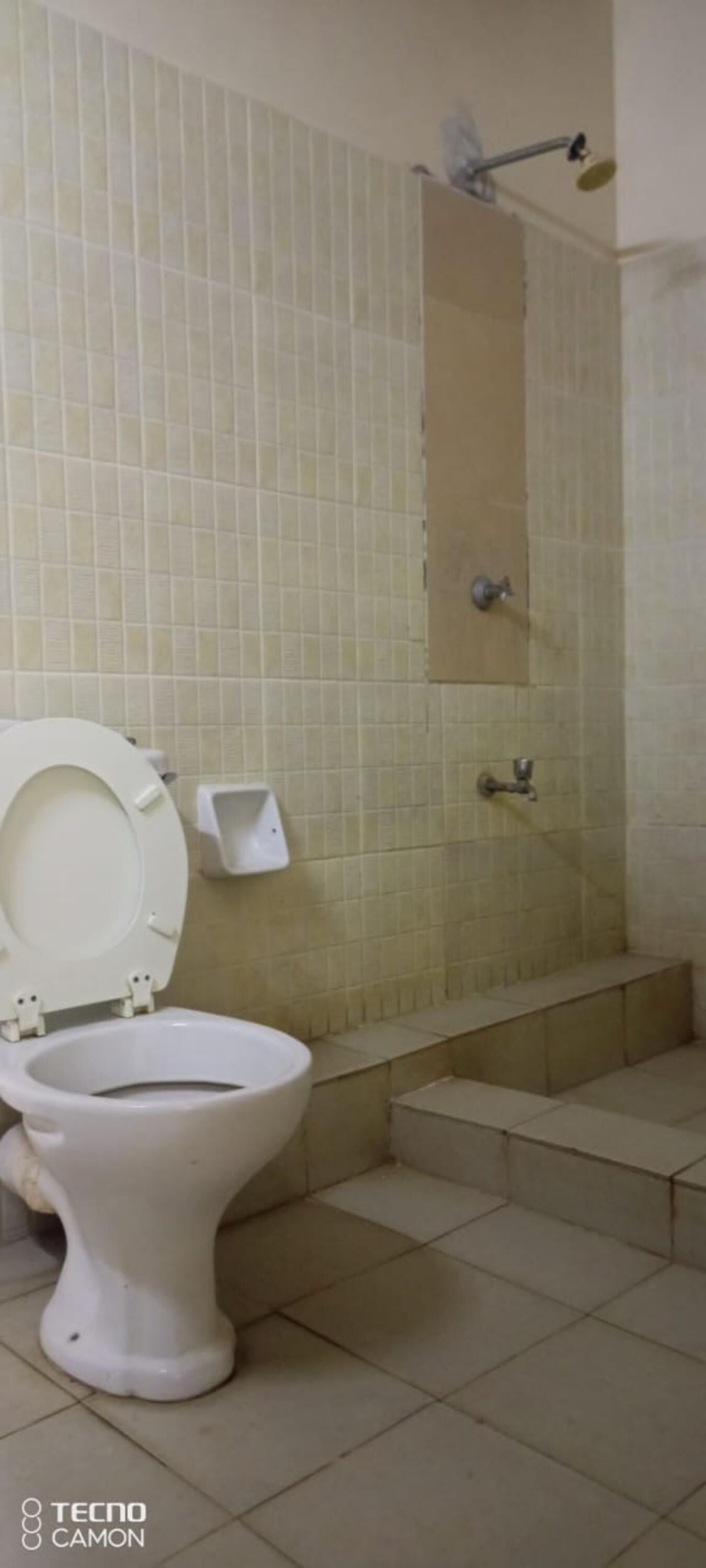 A bathroom with a toilet, a shower, and tiled walls.