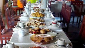 A long dining table with various dishes and teacups. - New Mahrus Hotel & Rooftop Restaurant (Lamu)