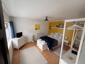 A bedroom with a bed, bedside table, TV, and a radiator.