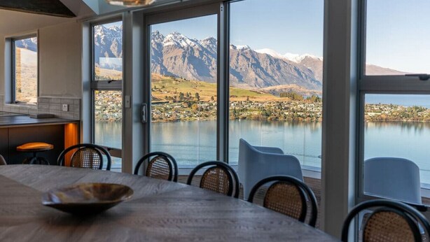 A dining area with a view of a lake and mountains. - Castle Cliff Lodge | Spa Pool + Sauna | Games Room (Queenstown)