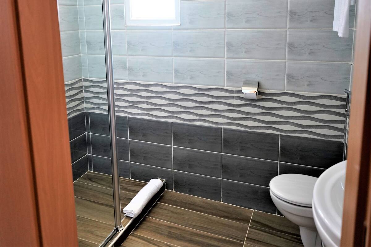 A bathroom with a shower, toilet, and a towel rack.