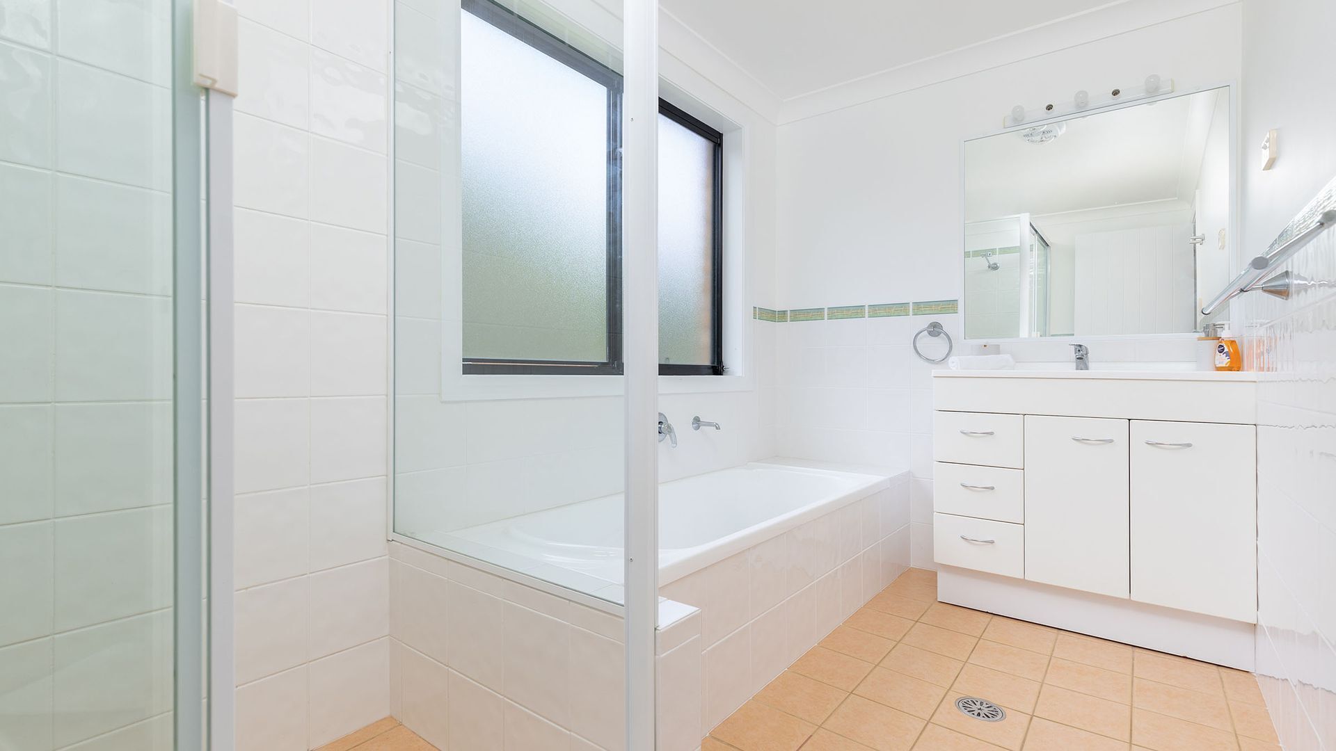 Une salle de bain moderne avec une douche à l’italienne en verre, une baignoire blanche et un meuble-lavabo avec un miroir.