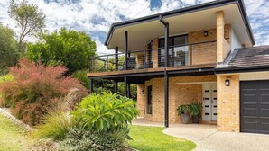 Una casa moderna de dos plantas con balcón, fachada de ladrillo y un jardín bien cuidado.