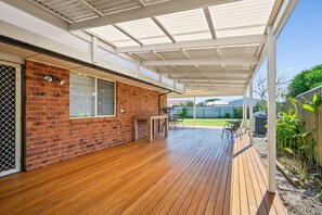 Une terrasse couverte avec une plateforme en bois, un mur en briques et une fenêtre.