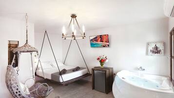 A modern bedroom with a hanging chair, a bed with a unique design, a large window, and a bathtub.