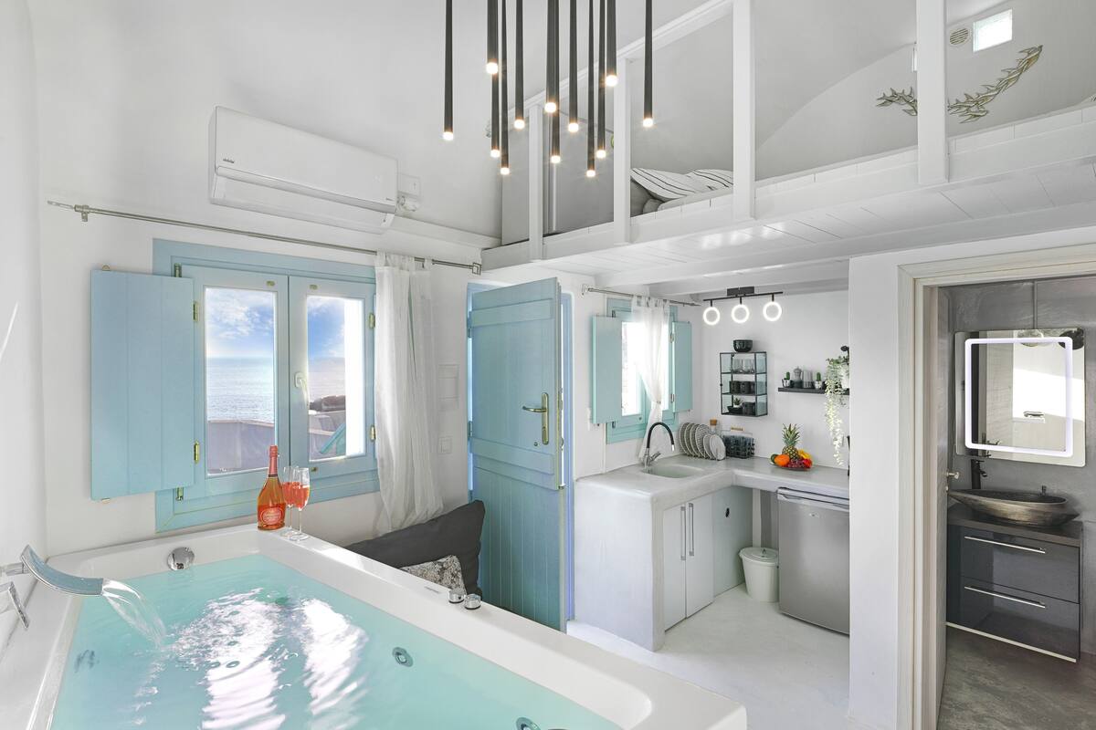 A modern bathroom with a bathtub, a sink, and a shower area. There is a window with curtains, a ceiling light fixture, and a mirror above the sink.
