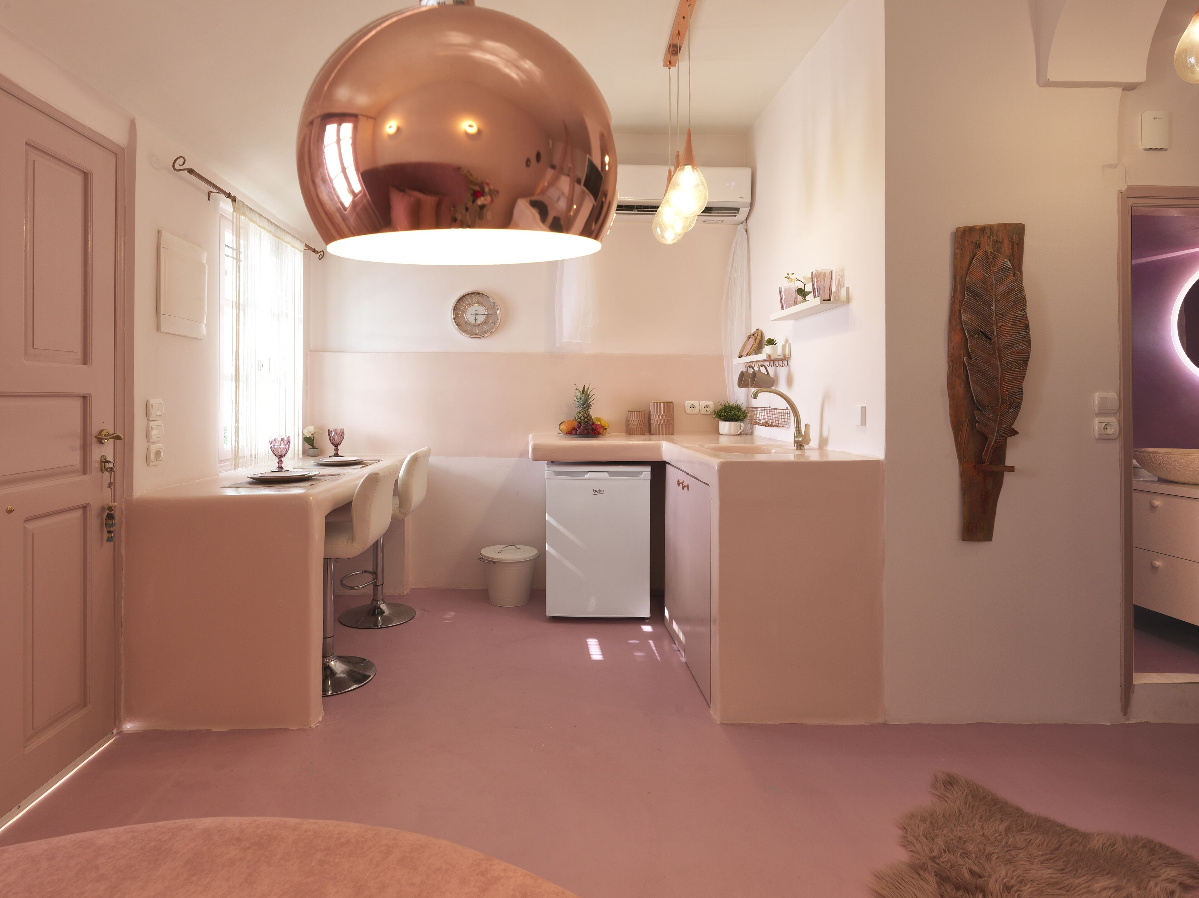 Una cocina moderna con una isla central, un refrigerador pequeño y una zona de comedor con mesa y sillas.