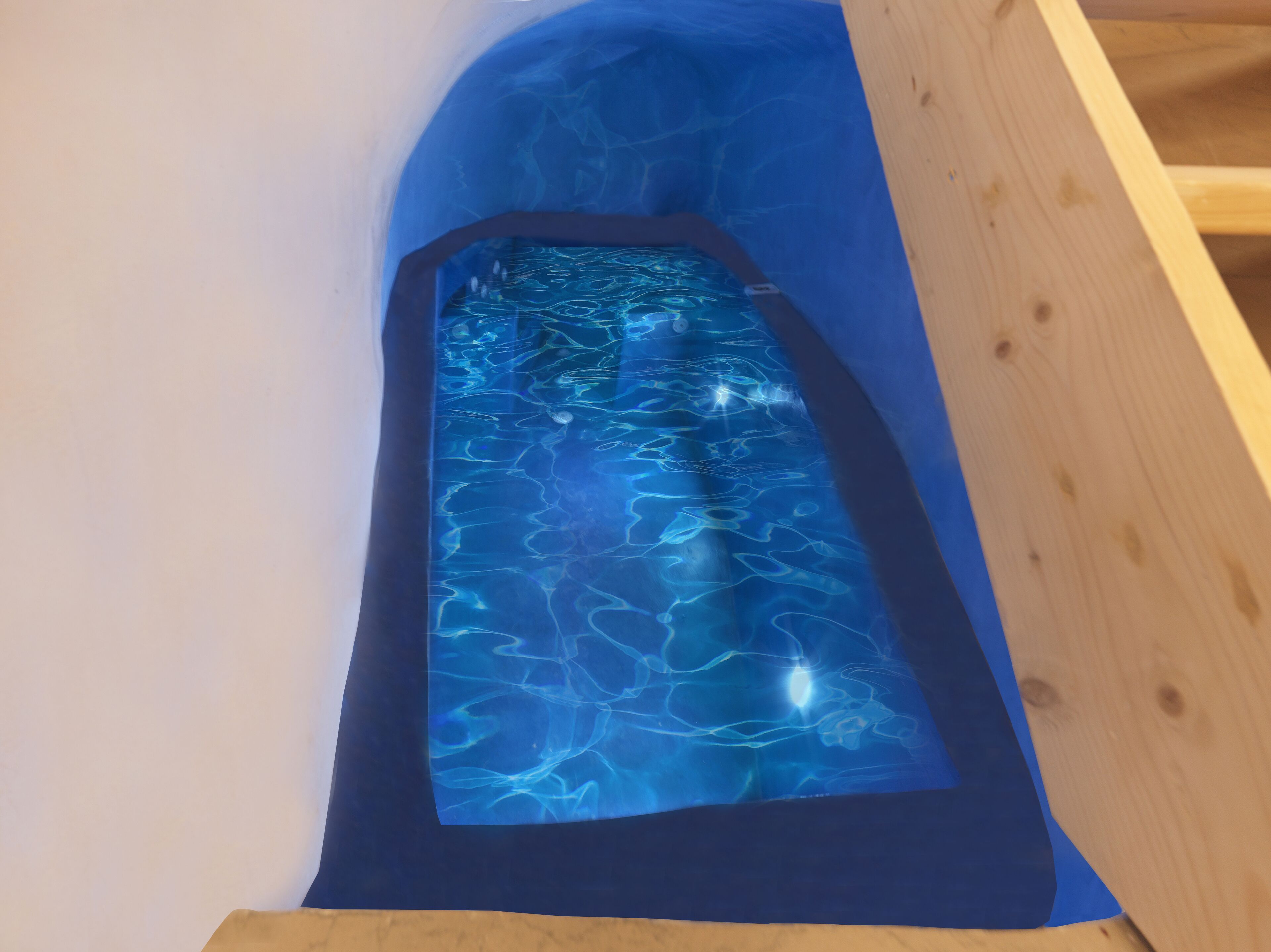 Une petite piscine étroite aux eaux d’un bleu limpide, entourée de murs en bois.