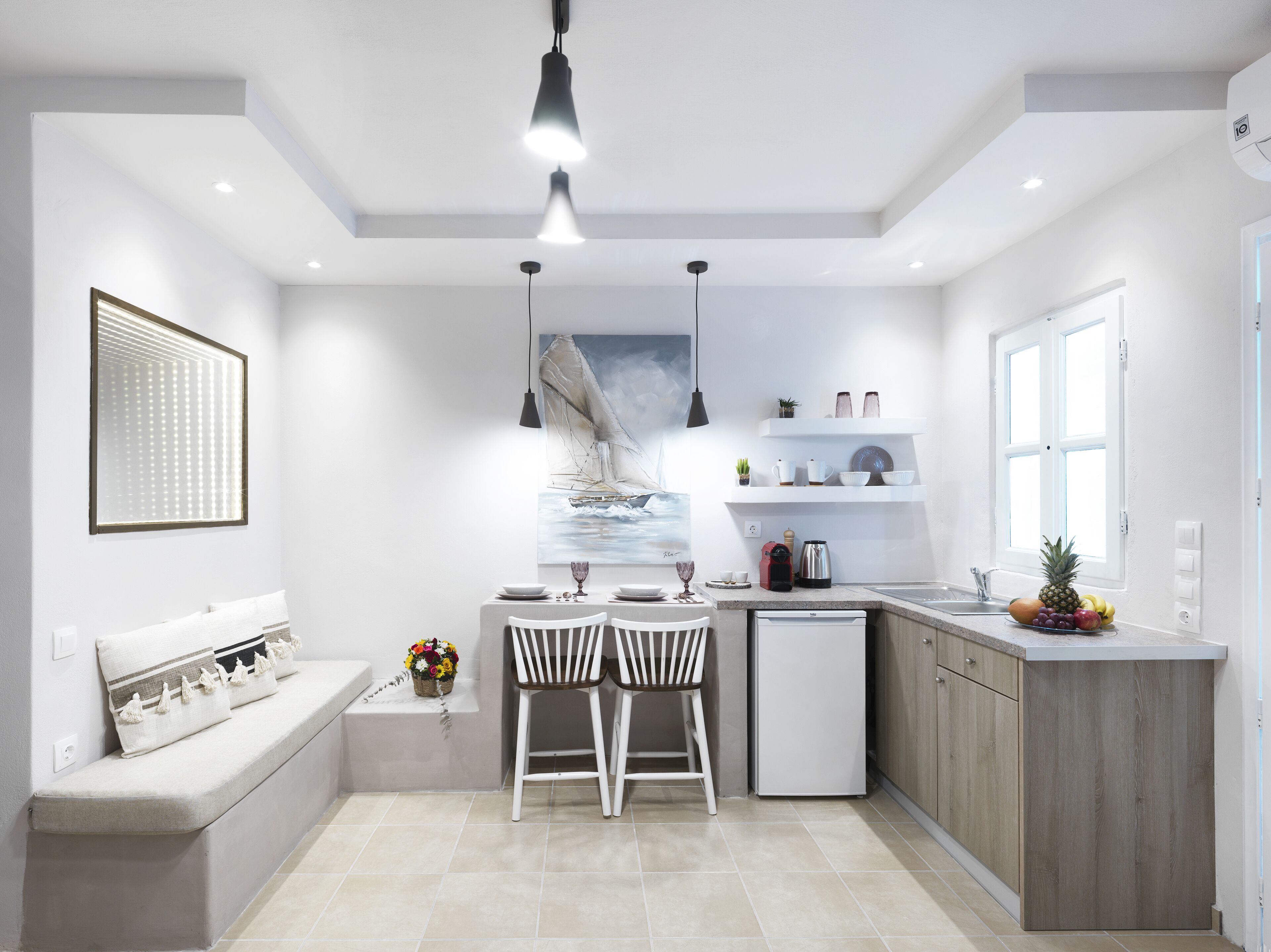 A modern kitchen with a dining area, featuring a built-in oven, a sink, and a window with a view.