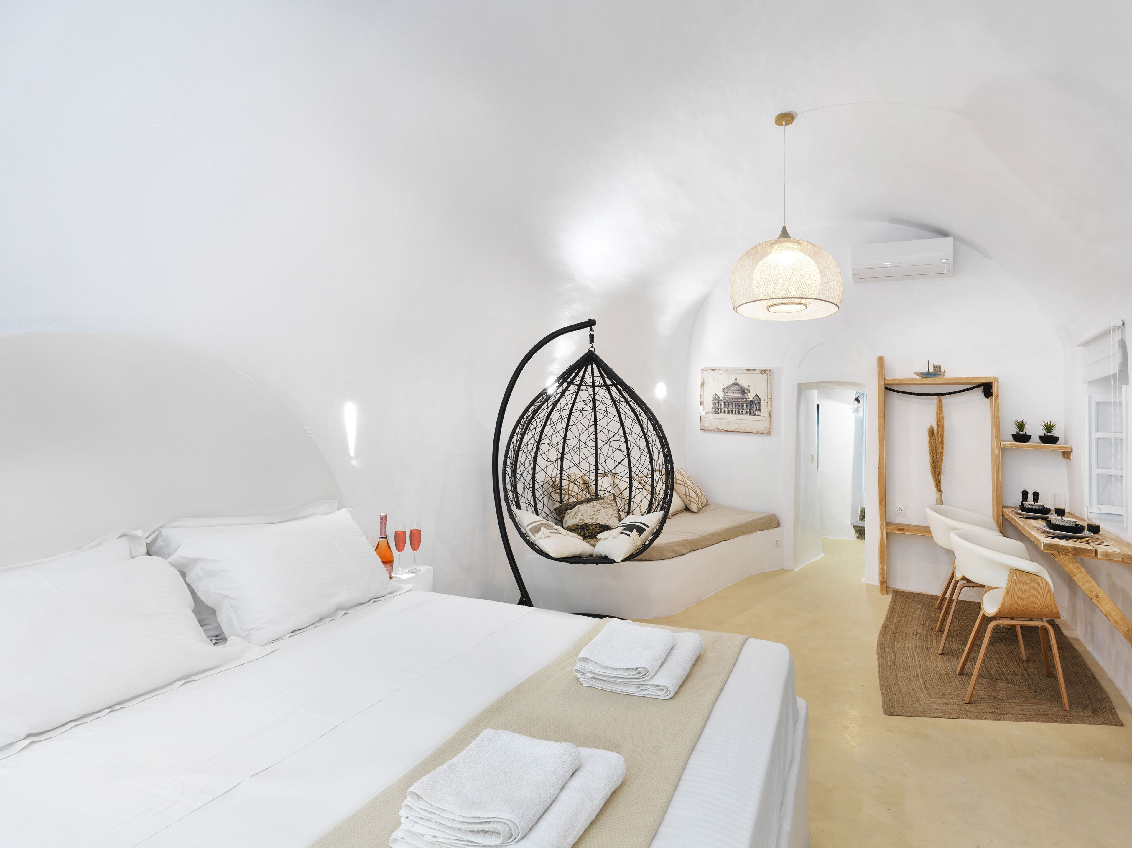 Een moderne, minimalistische slaapkamer met een hangstoel, een bureau en een klein zithoekje.