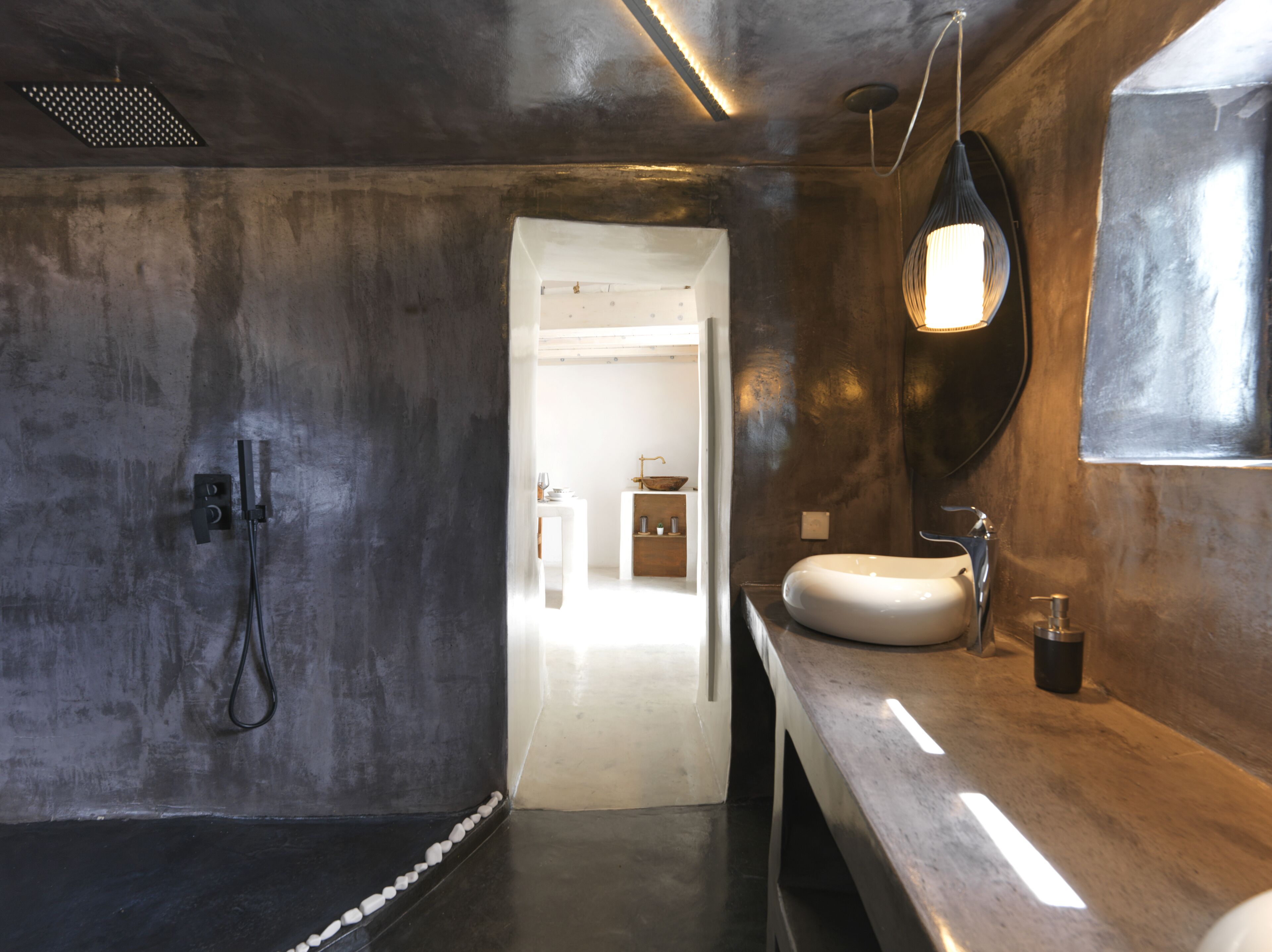 Une salle de bain moderne avec un grand miroir, un lavabo et un espace douche.