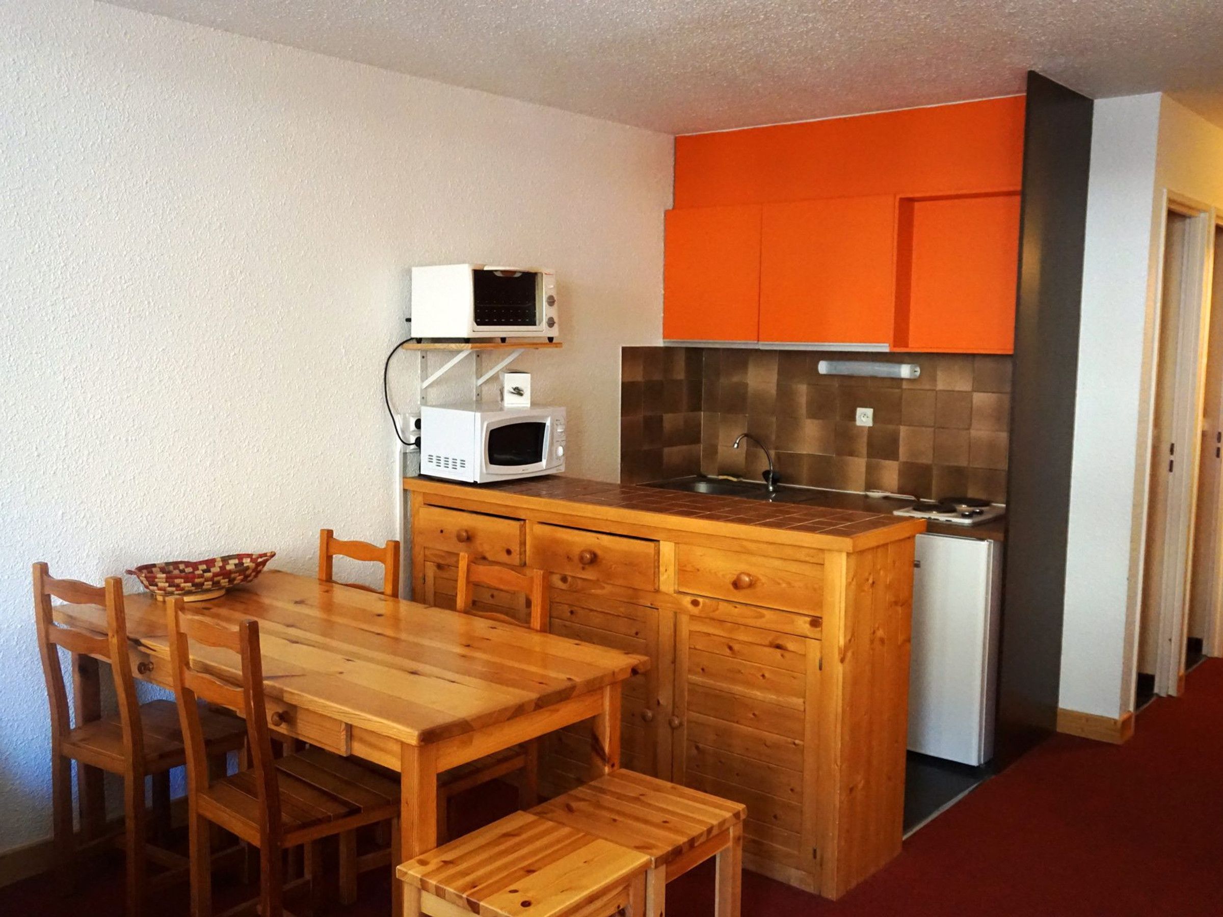 A compact kitchen with wooden cabinetry, a microwave, and a sink.