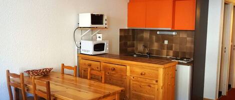 A compact kitchen with wooden cabinetry, a microwave, and a sink.