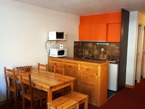 A compact kitchen with wooden cabinetry, a microwave, and a sink.