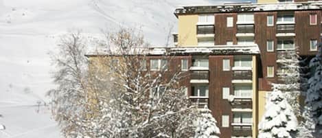 A multi-story building with a snow-covered roof and surrounding trees.