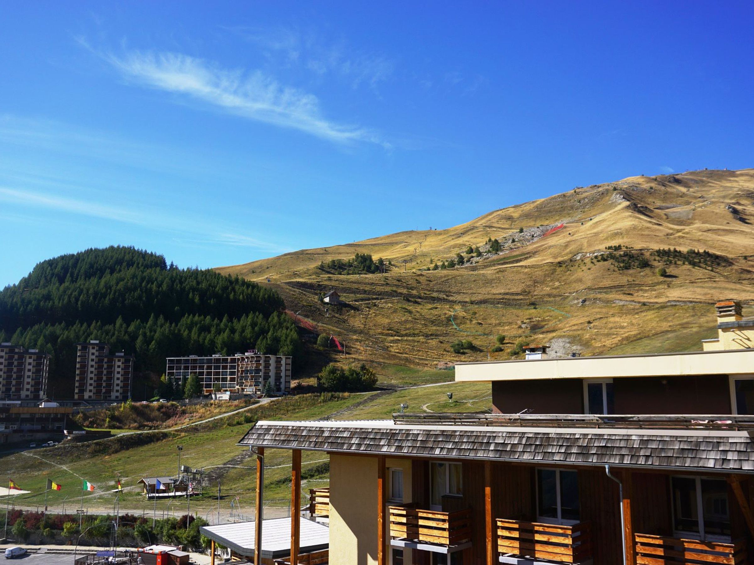 A hotel with a wooden facade, a balcony, and a view of a mountainous landscape.