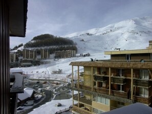 A multi-story building with balconies, a ski slope in the background, and a snow-covered landscape. - Studio cabin, pets welcome - 4 guests (Orcières Merlette)