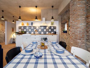 A dining area with a checkered tablecloth, white chairs, and blue and white plates.