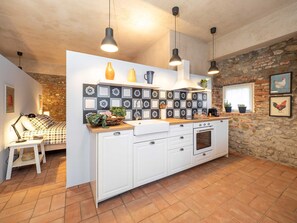 A modern kitchen with white cabinets, a stone wall, and a tiled backsplash.