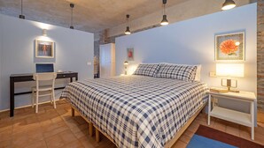 A bedroom with a bed, desk, chair, and bedside tables. - Peaceful Apartment with Garden in Farmhouse Resort (Cressa)