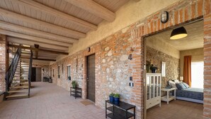 A spacious hallway with a wooden staircase, stone walls, and a bed with a view.