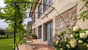 Un edificio moderno con facciata in mattoni, ampie finestre e un patio lastricato con posti a sedere esterni.