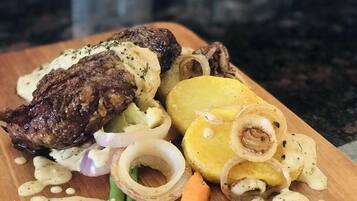 A meal consisting of steak, potatoes, and onions on a wooden board.