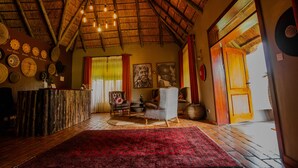 Une pièce avec un plafond en bois, un comptoir d’accueil, une moquette rouge et un grand tableau accroché au mur.
