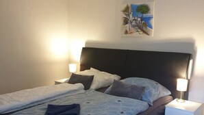 A bedroom with a bed, two bedside tables, a nightstand, and a wall-mounted painting. - Pure relaxation with Nina (Bad Lauterberg im Harz)