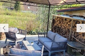 An outdoor seating area with wicker furniture and a table, a stack of firewood, and a covered structure. - Pure relaxation with Nina (Bad Lauterberg im Harz)