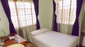 A bedroom with a bed, a bedside table with a lamp, a window with curtains, and a bathroom with a sink and mirror. - Express Inn (Nyeri)