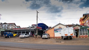A commercial area with multiple businesses, including a hotel named 'Express Inn' and a restaurant called 'Express Brewing'. There are several parked vehicles, including cars and a truck. - Express Inn (Nyeri)