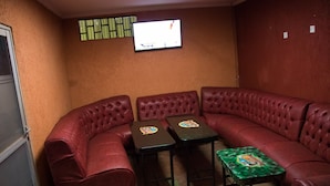 A corner seating area with red leather couches and two small tables with decorative tops. - Express Inn (Nyeri)