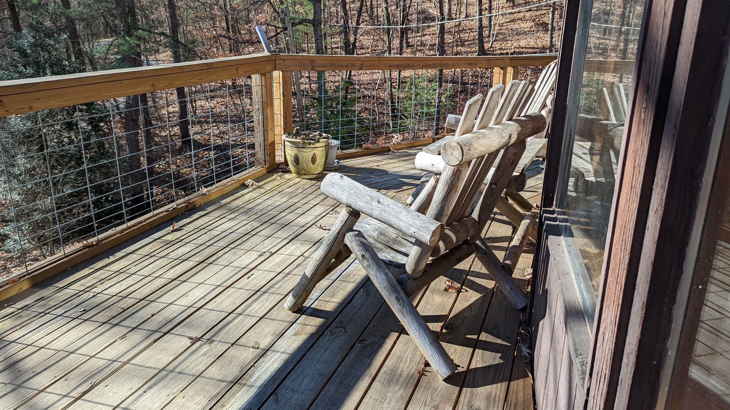 A wooden deck with a railing, a bench, and a potted plant.