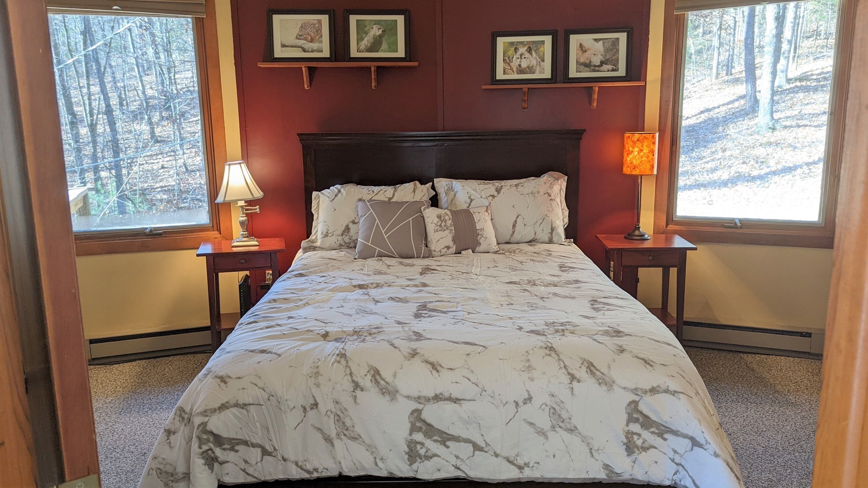 A bedroom with a large bed, two bedside tables, a headboard, and framed pictures on the wall.
