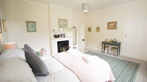 Une chambre à coucher comprenant un lit, une table de chevet, une commode et une cheminée.