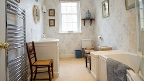 Une salle de bain équipée d’une baignoire, de toilettes, d’un lavabo et d’une chaise.