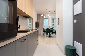 A modern kitchen with dark cabinets, a wooden countertop, and a dining area with a table and chairs.