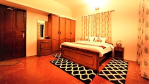 A bedroom with a wooden bed, a wardrobe, a nightstand, and a patterned rug. - ONELOVEDALE Blusalz Homes (Ootacamund)