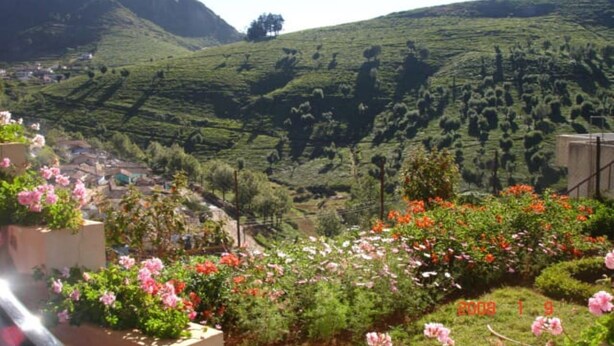 A rural landscape with terraced fields, a small village, and blooming flowers. - ONELOVEDALE Blusalz Homes (Ootacamund)