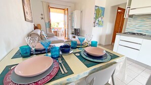A dining area with a table set for four, featuring pink plates, blue glassware, and a map on the wall.