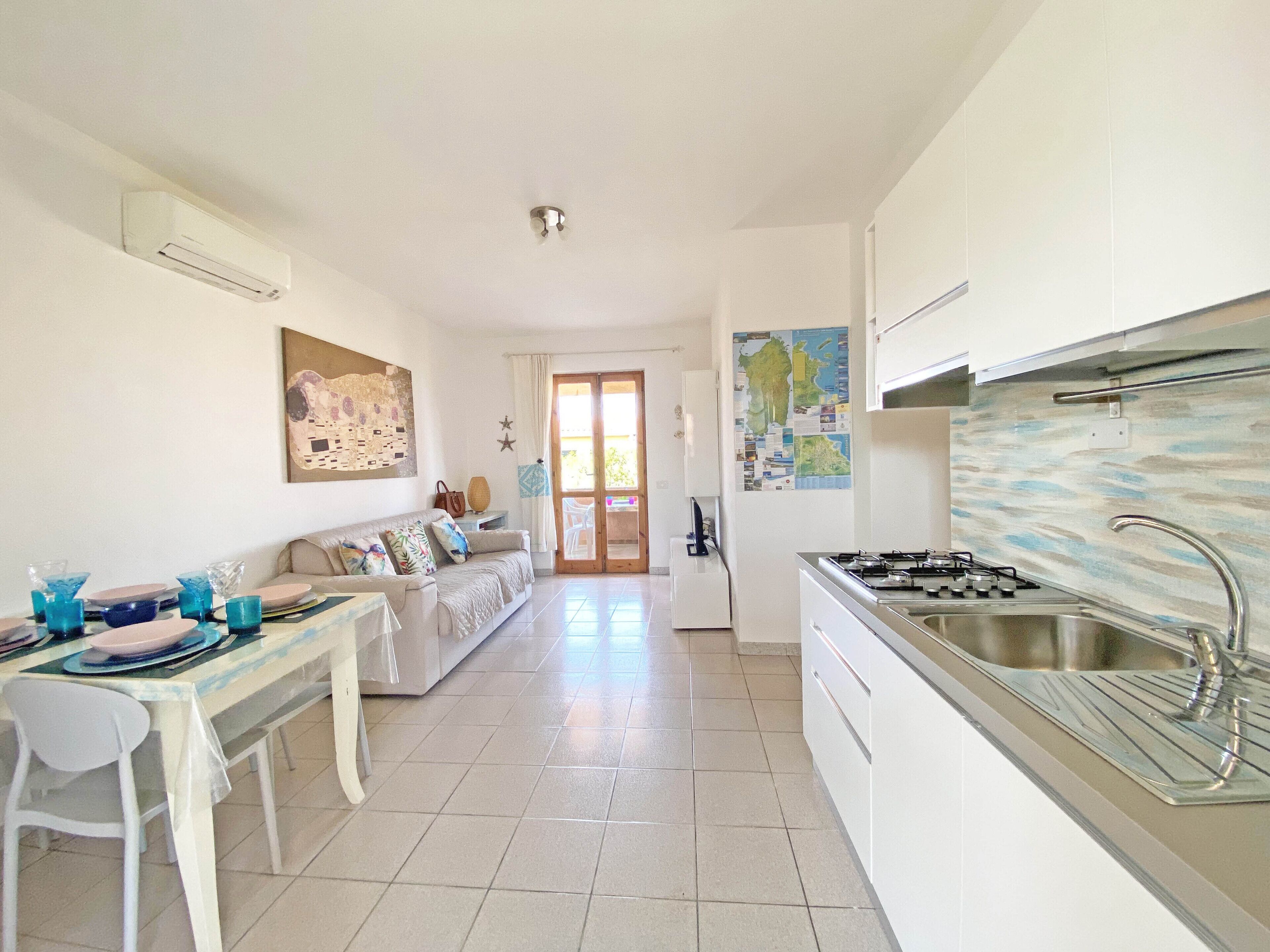 A modern kitchen with a gas stove, a sink, and a dining area with a white table and chairs.