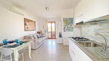 A modern kitchen with a gas stove, a sink, and a dining area with a white table and chairs.