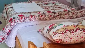 Una cama doble con ropa de cama estampada con motivos florales y cabecero de madera.