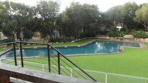 Piscina com deck de madeira e área gramada.