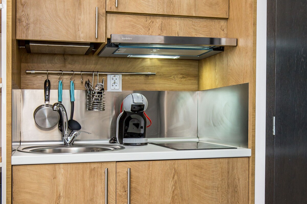 A compact kitchen with wooden cabinets, a stainless steel sink, and a coffee machine.