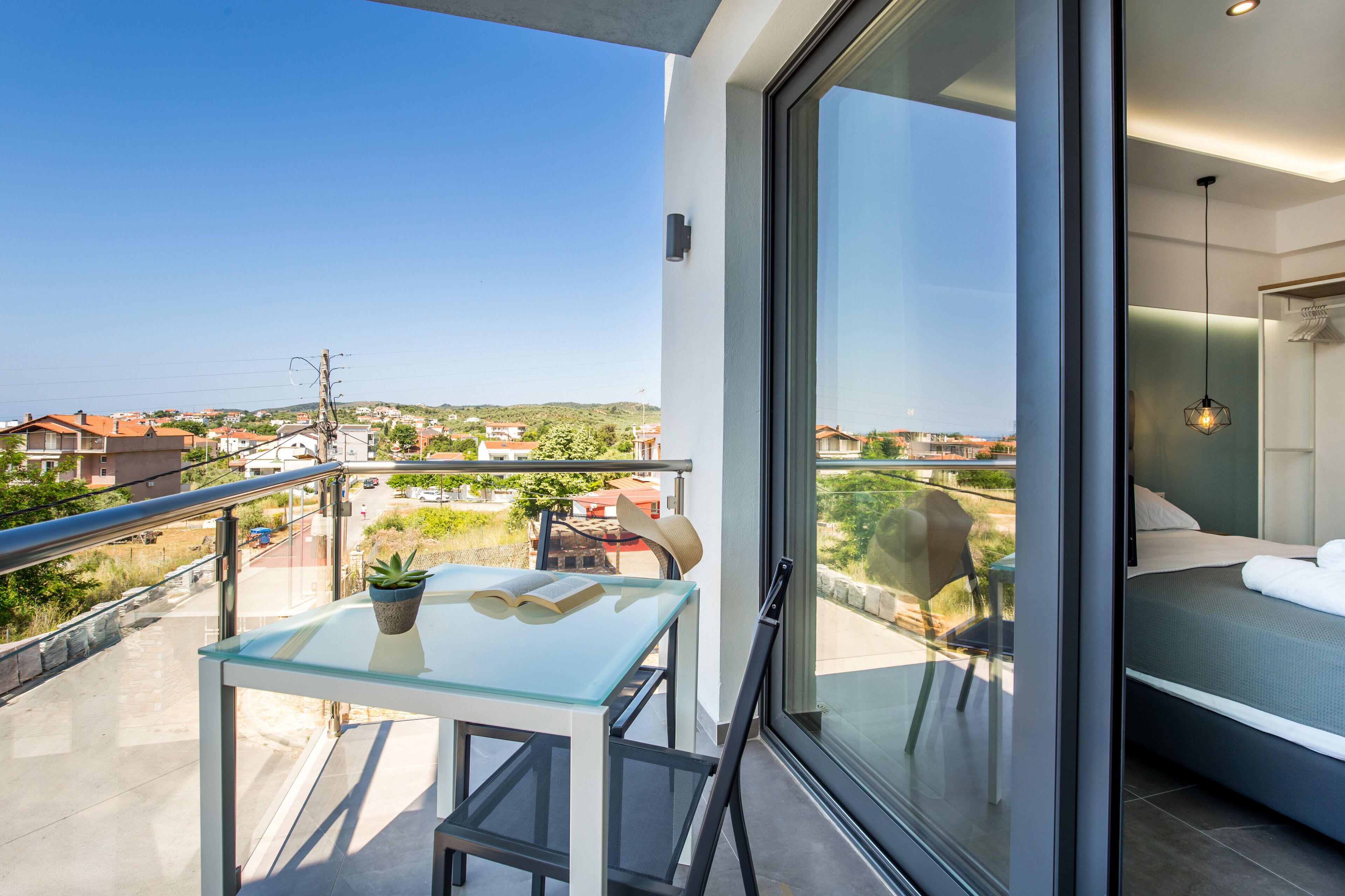 Un balcon avec une table en verre, une chaise et un pot de fleurs.